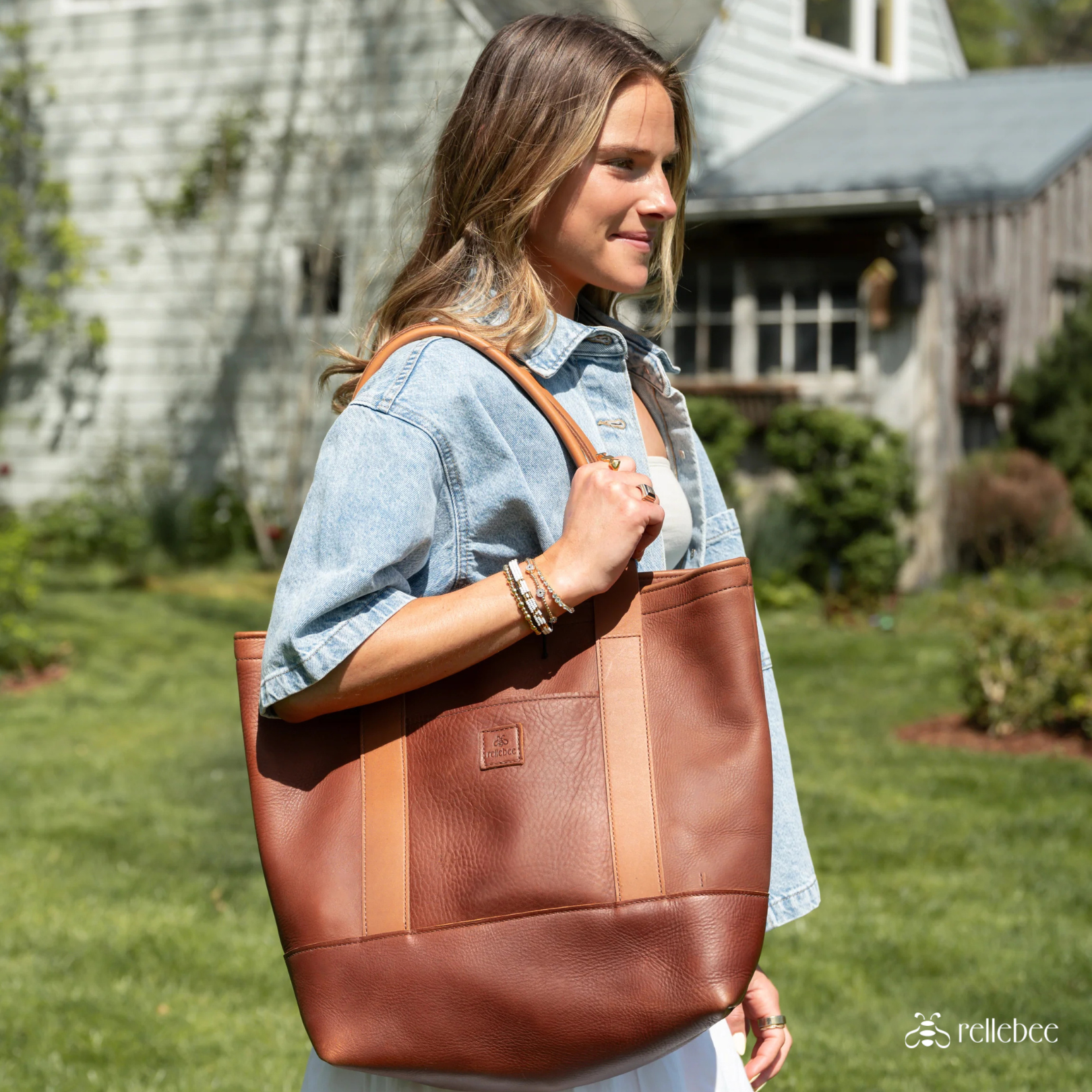woman holding a leather tote bag on her shoulder
