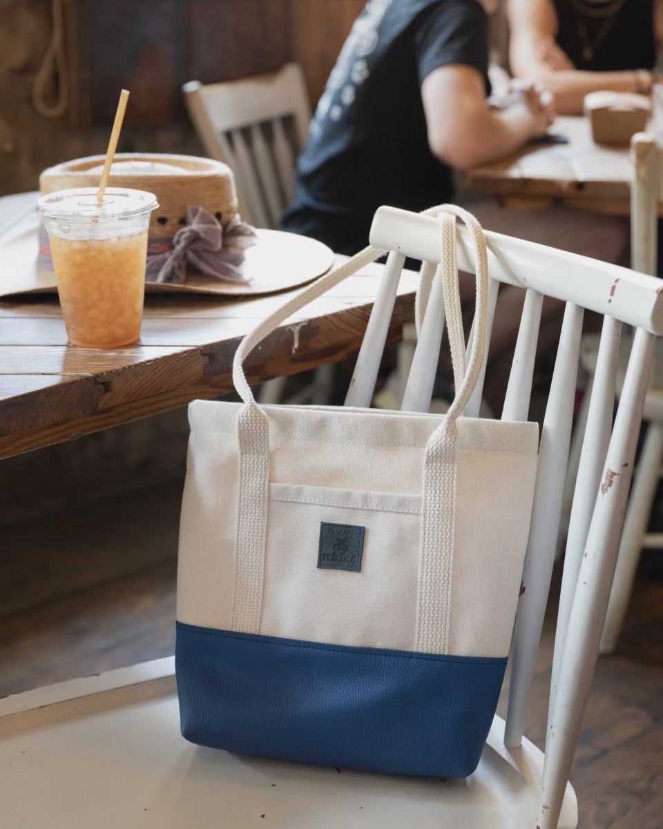 Image of product Little Everyday Tote in Blueberry + Canvas: Just like the Everyday but smaller. This is the perfect bag to throw on your shoulder everyday for any casual outing. Holds a water bottle, keys, clutch, sunglasses and a book. Outside pocket perfect spot for your phone. It's a cute bag!