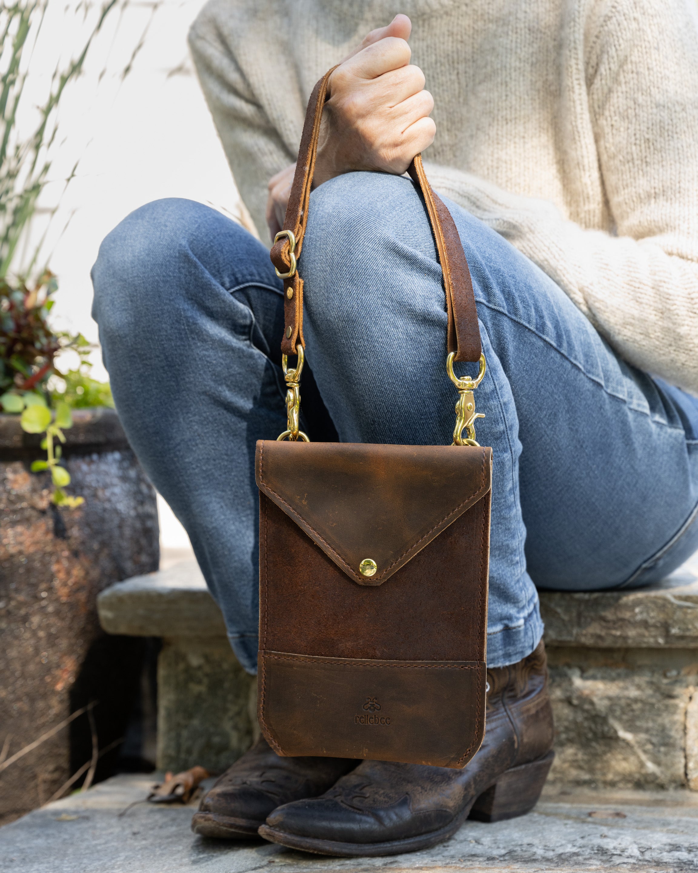 Closeup image of model sitting down and holding the Envelope sling