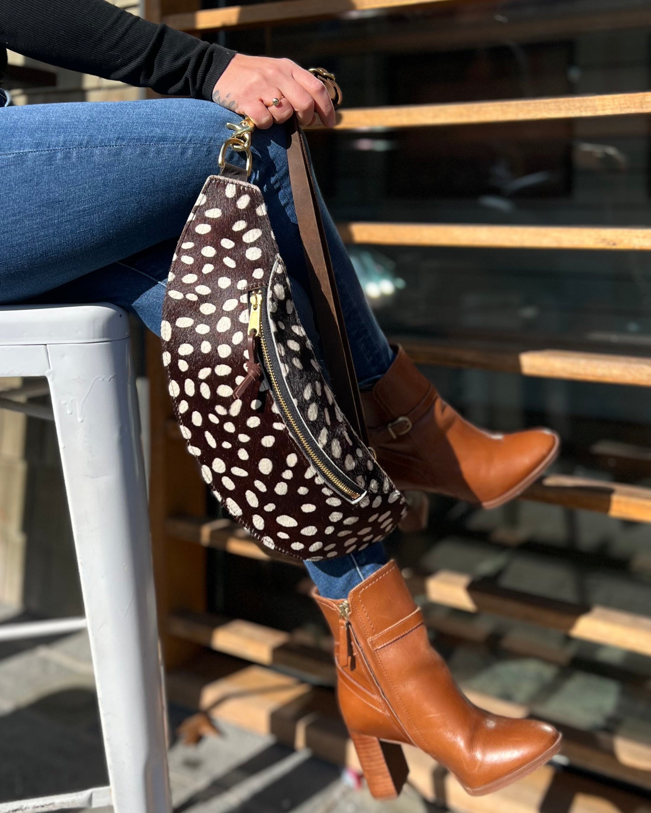 Image of model holding the classic sling:Hair-on-hide in coco dot.