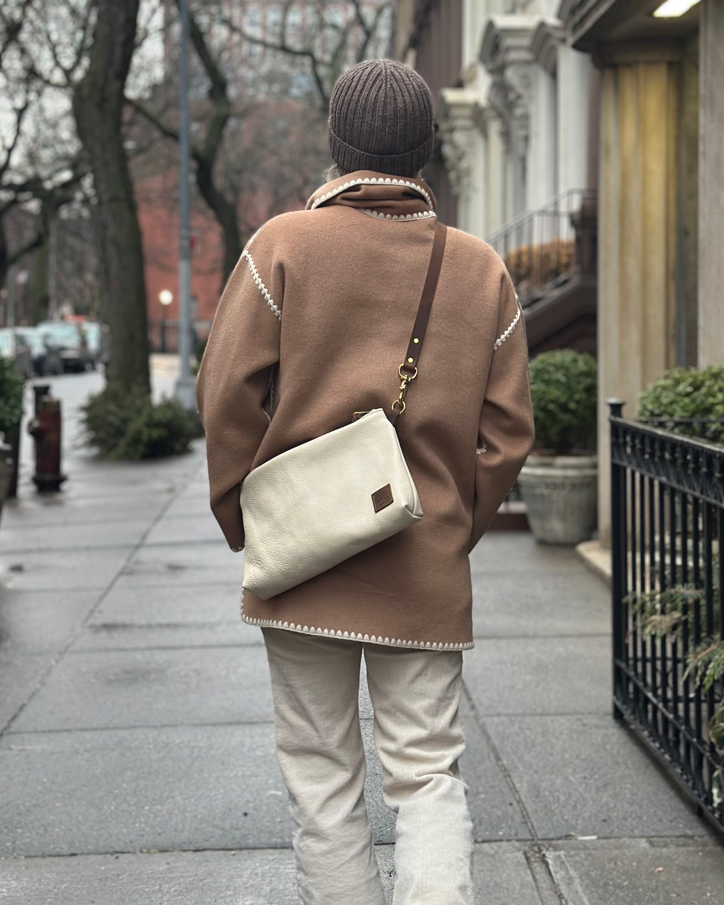 Back view image of model wearing the Brooklyn Sling in oat milk while walking