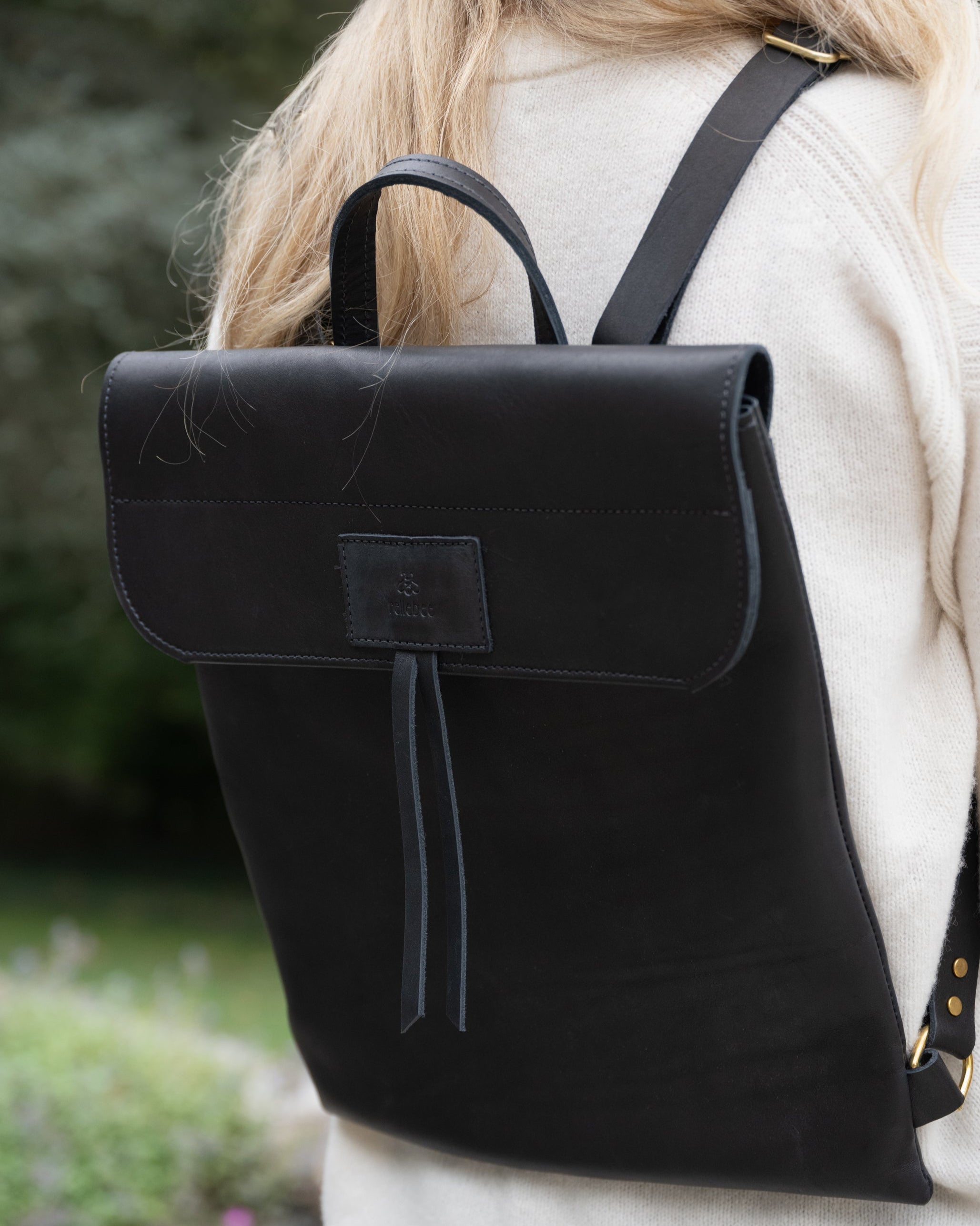 Closeup view of Model wearing the product Messenger Pack in Jet Black. The perfect go to bag for your laptop, notebook, folder, clutch and other items. Inside pocket. Strong magnetic closure. The two leather strips function well for easy access and a pop of personality. Made up in a sturdy Olive Brown and a Jet Black hide from Wisconsin. Black topstitching. This bag is sleek and sophisticated. It will take you through any important meeting or wherever adventure leads you.