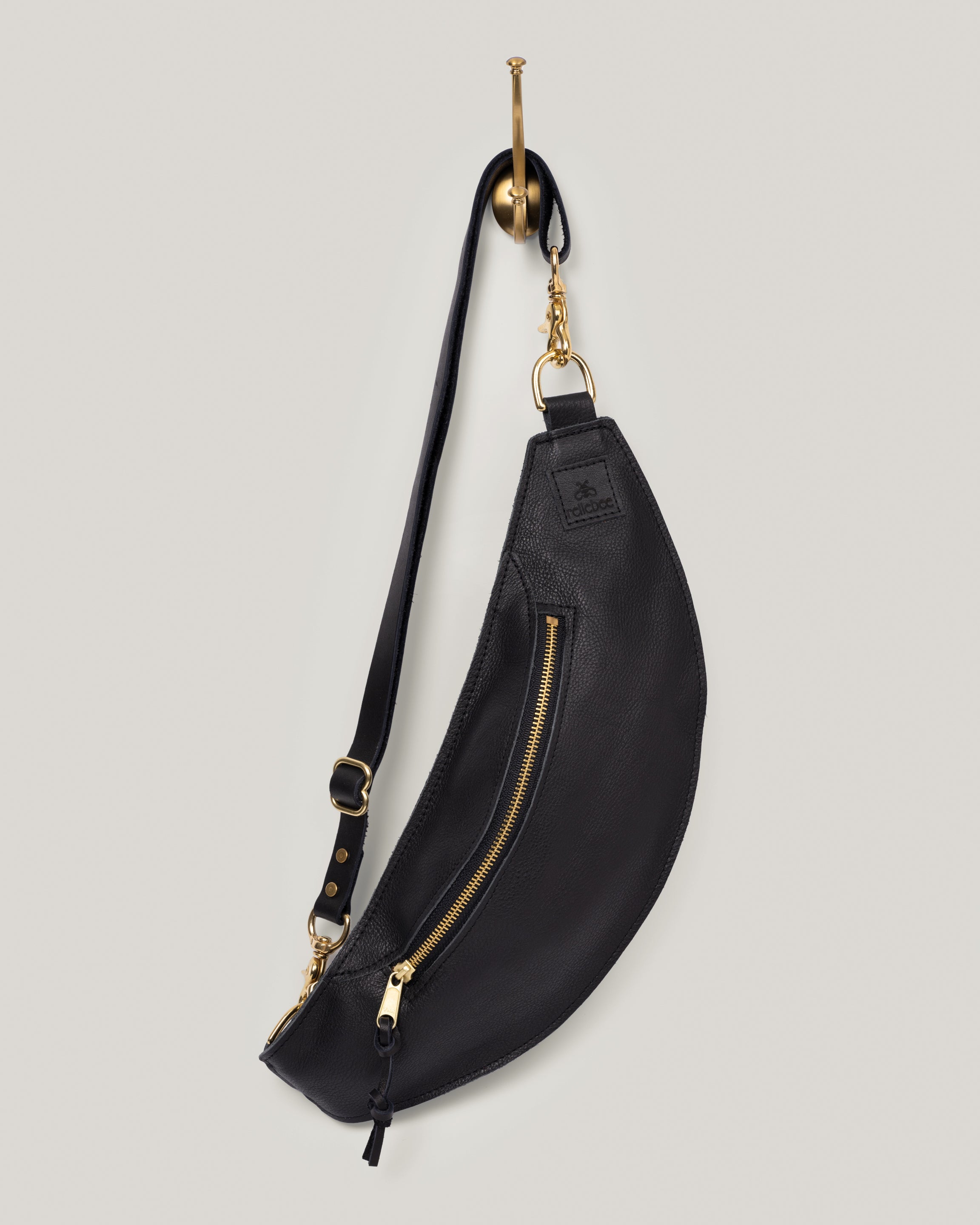 Image of product Classic sling in jet black: The Classic Sling is low profile and gently hugs your body. Just big enough to hold your phone, keys, mini wallet and chapstick. Adjustable bridle leather straps. Sturdy top of the line antique brass hardware and zipper.