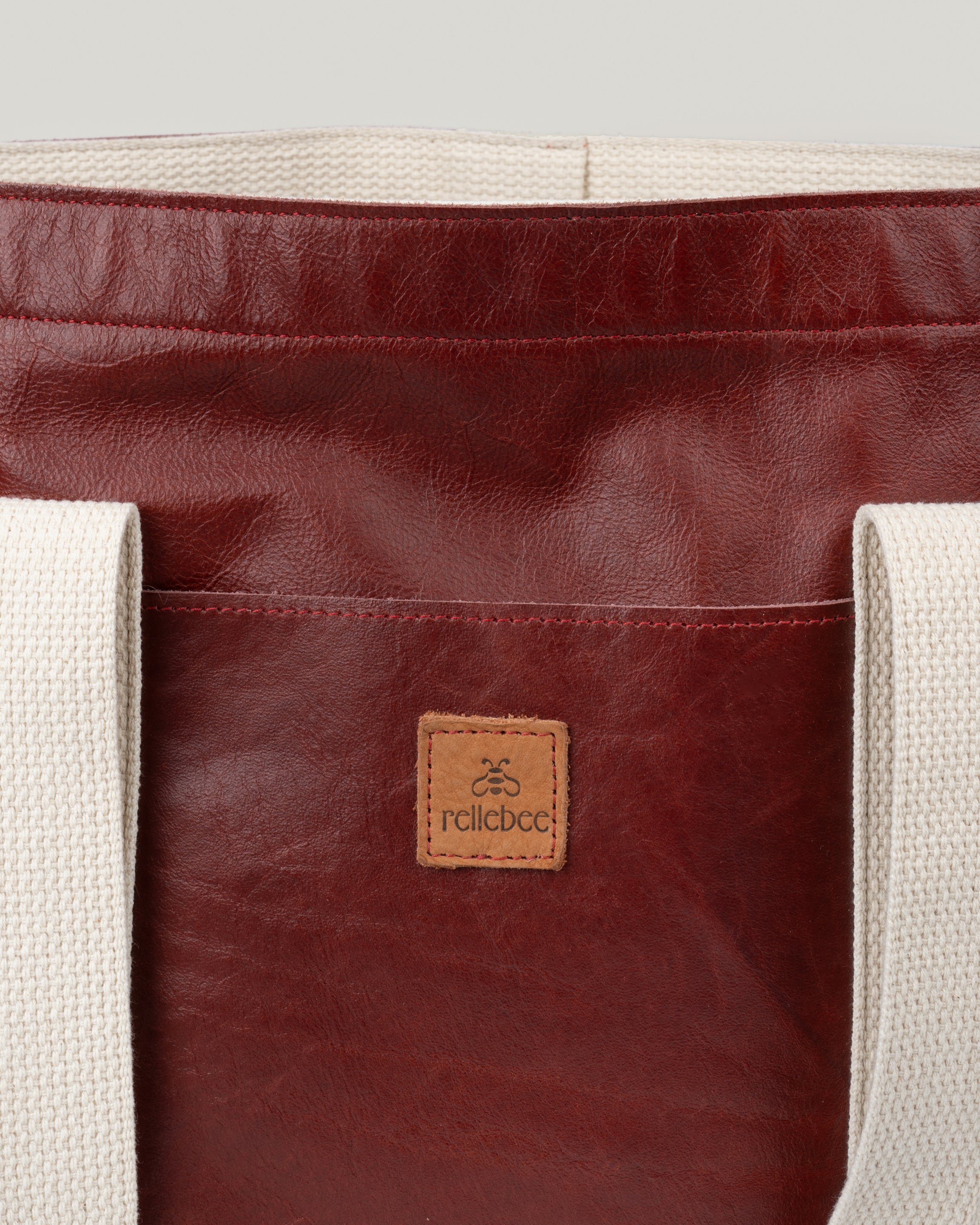 Closeup image of Everyday Tote: Leather on Leather in Crimson. Showing the Rellebee logo