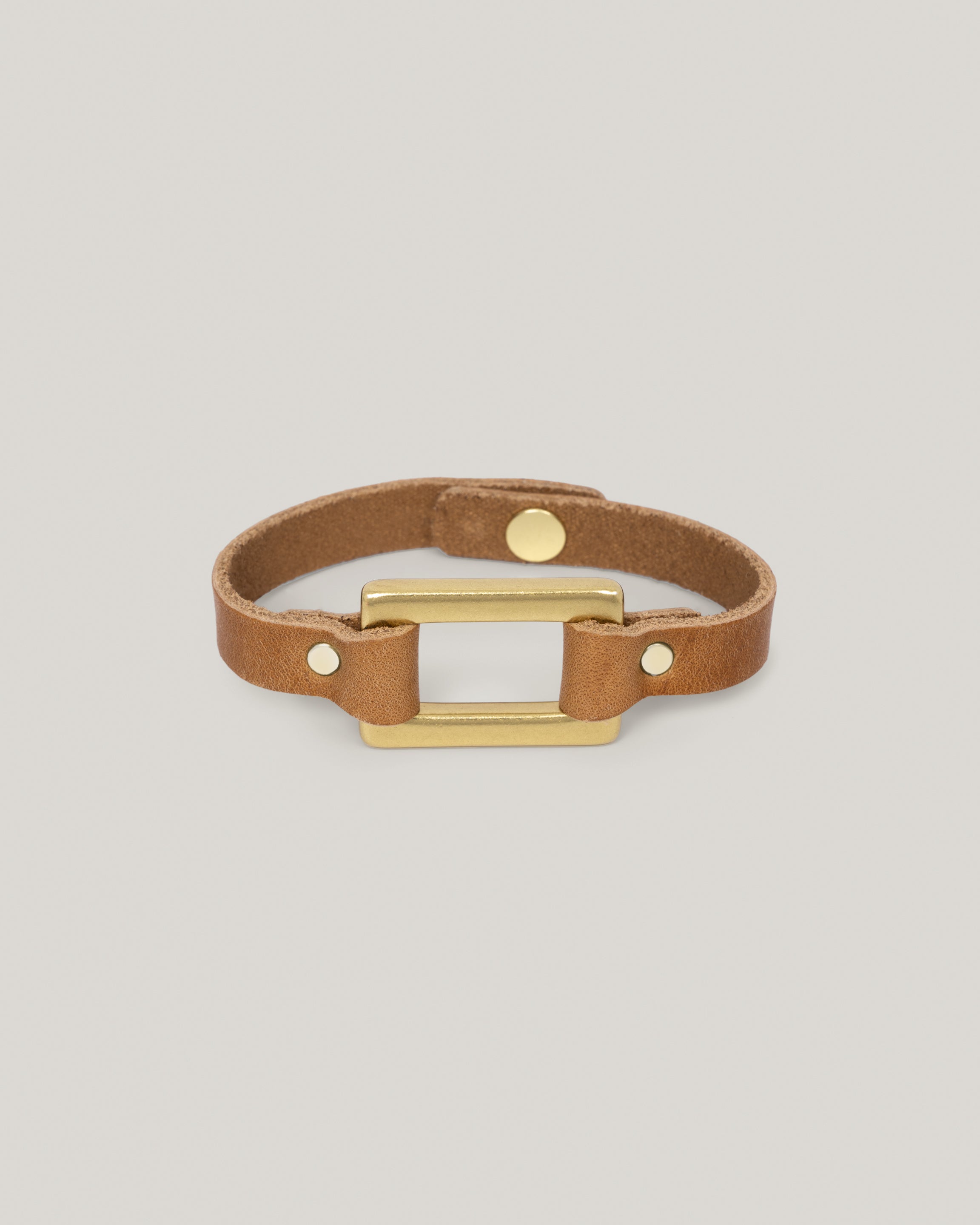 Image of the Stirrup bracelet in sand: Made from sturdy 5 ounce full grain leather. A nod to the horse country. Dress it up. Dress it down. Looks great layered. Pretty polished brass rectangle ring adds a touch of sophistication. Made by our leather craftsmen friends in Wyoming. 