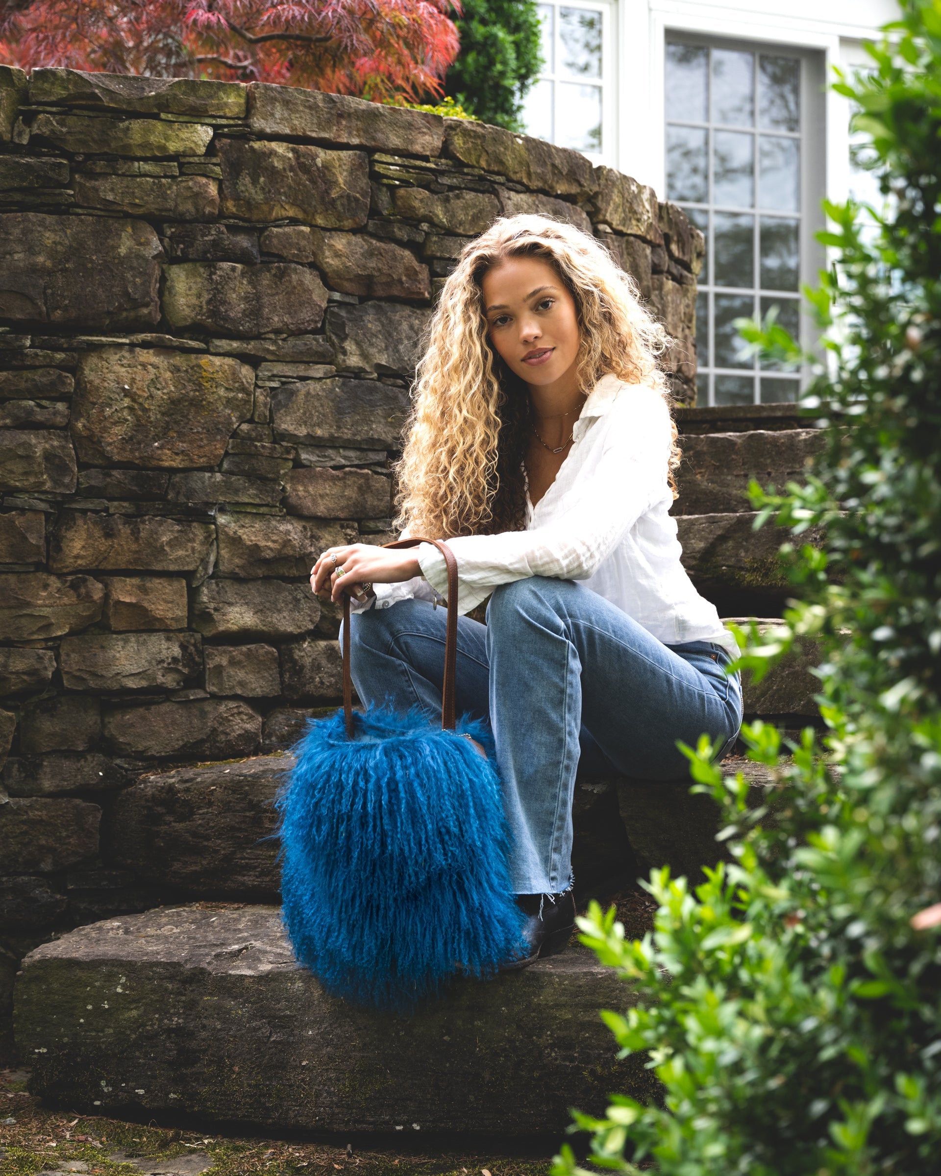 Image of model holding the product Mongolian in Sky Blue(unlined):The Mongolian is loaded with personality. Simple shape. Single leather strap with topstitching. Just big enough for your phone, water bottle, sunglasses, clutch, wallet and keys. This bag blows in the wind and moves right along with you. You won't want to put it down. Vintage vibe. Lined with an inside pocket.