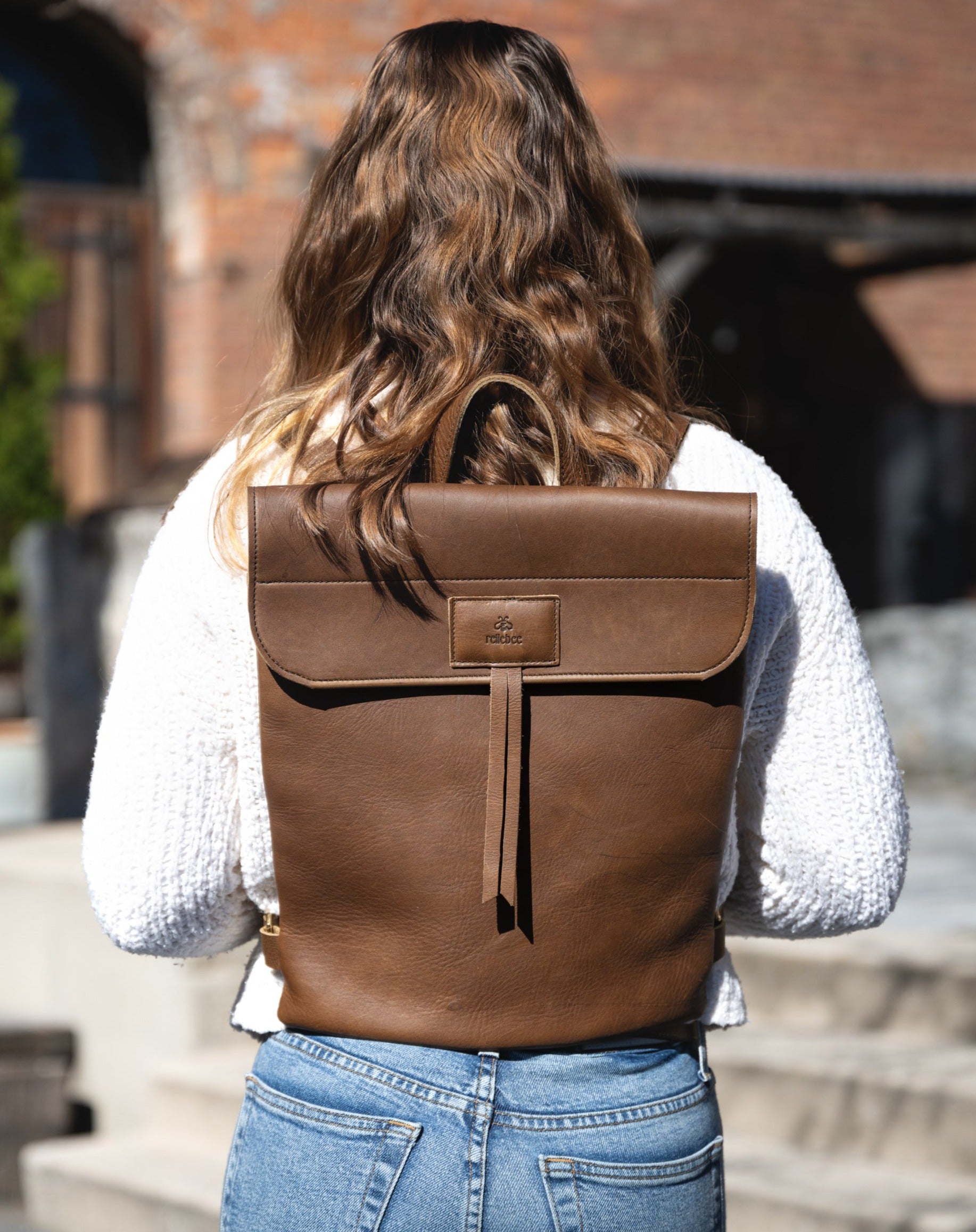 Back view image of model wearing the Messenger Pack in Olive Brown