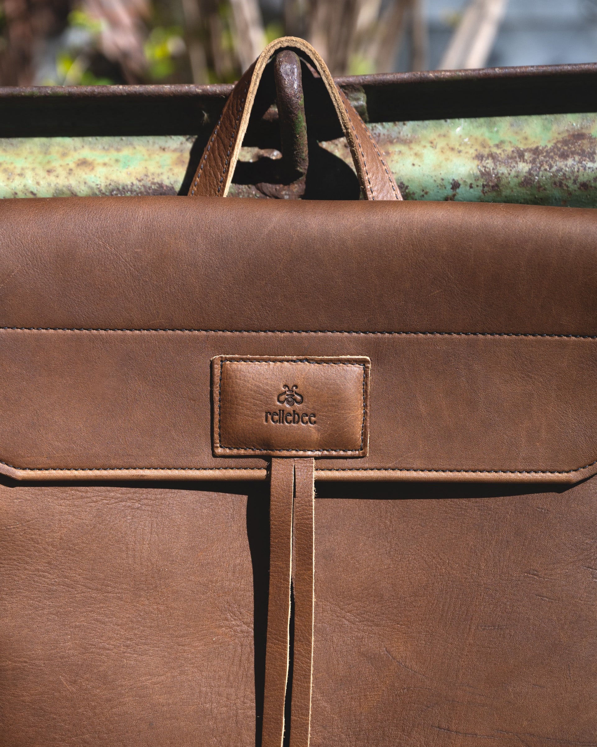 Closeup view of the front of the Messenger pack in Olive brown. Highlighting the Rellebee logo