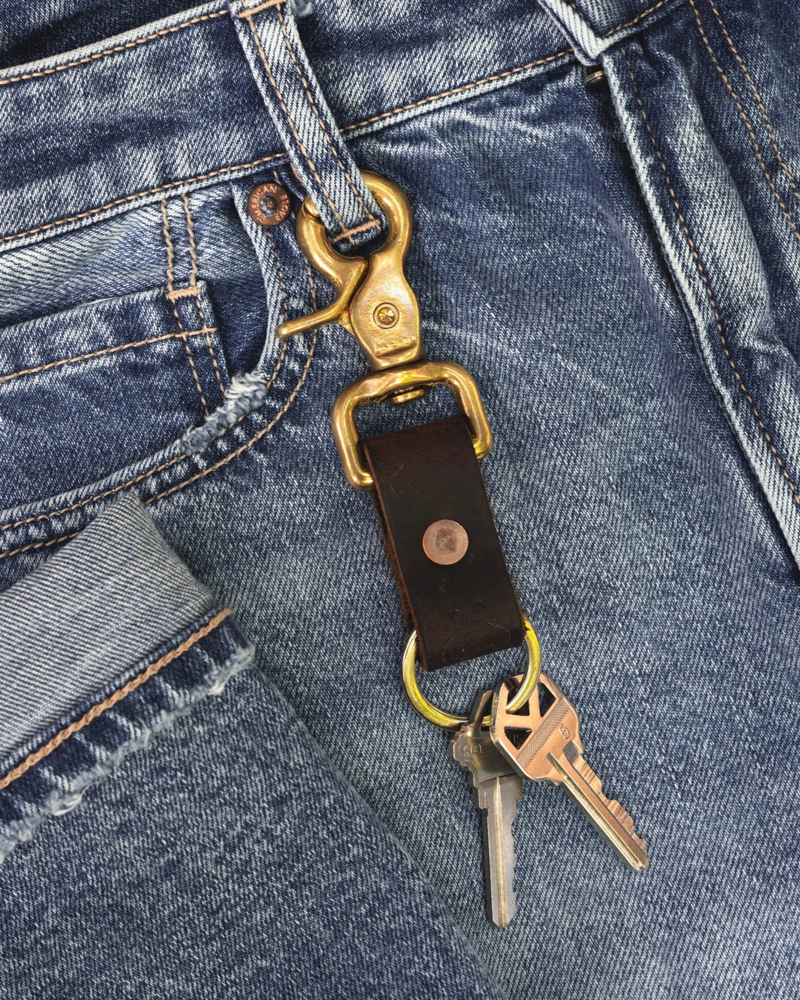 Closeup image of Brass Key Ring hooked onto jeans