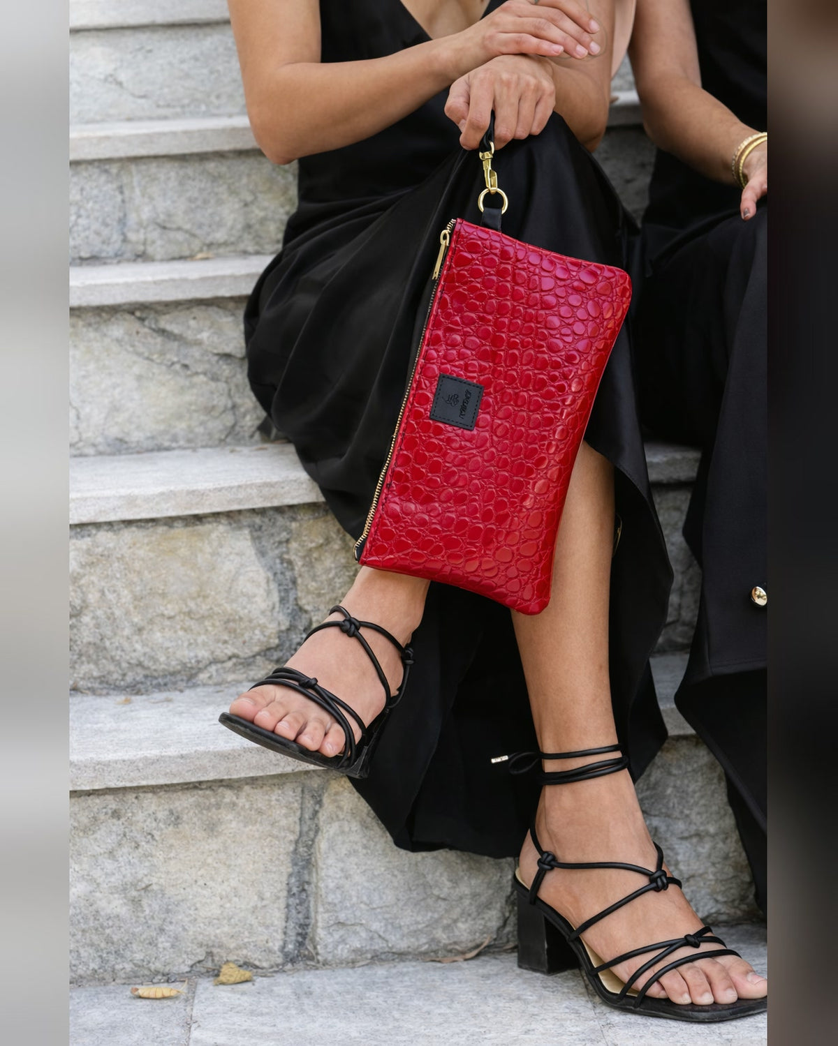 Woman in a black dress holding The Clutch in Red