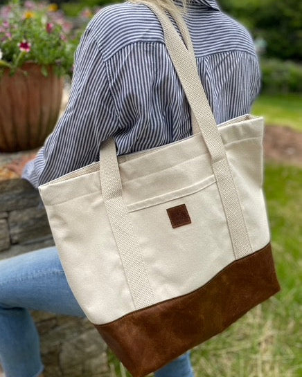 Image of the product Everyday Tote: Canvas on Leather in Chestnut brown. Nice and roomy. Great casual bag for work, school, and everyday living. The outside pocket is the perfect spot to slip your phone and keys into.