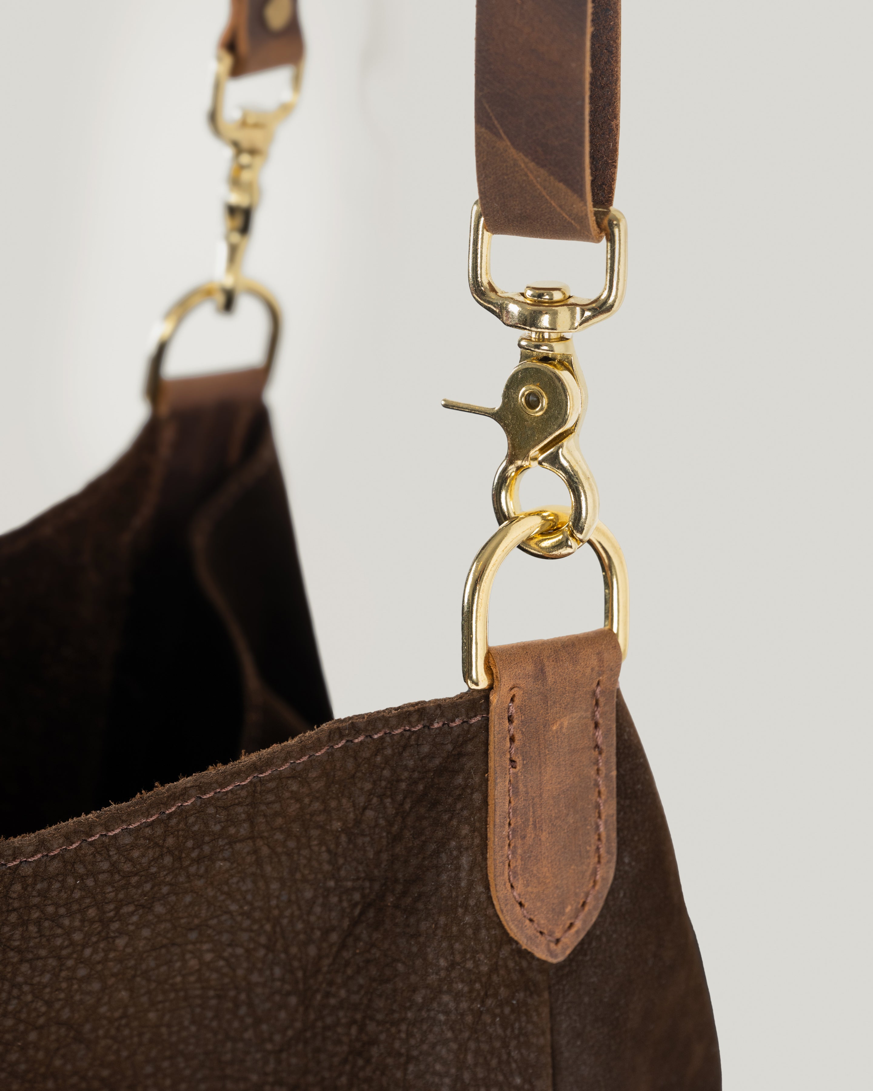 Adjustable brown leather bridle strap and brass hardware detail on The Slouch crossbody bag