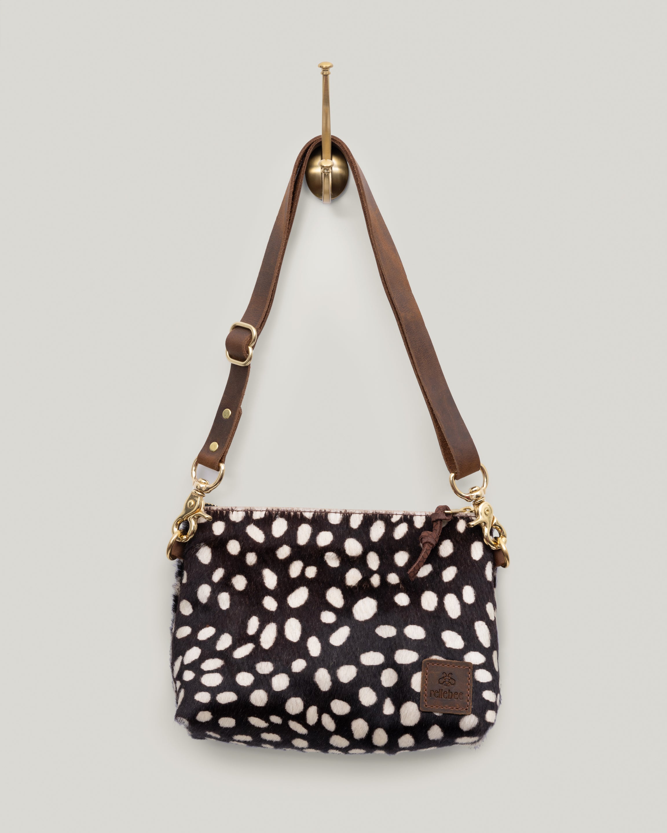 Image of the product Little Brooklyn sling in coco-dot hair on hide:The Little Brooklyn Sling is just like the Brooklyn but a bit smaller. It's wedge in shape and extremely versatile. Wear it as a sling across the body or shorten the bridle strap and wear snuggly over your shoulder, tucked under your arm. Unsnap the strap and carry it as a clutch. Three bags in one:) The Little Brooklyn is made up in the cozy Natural New Zealand Shearling.