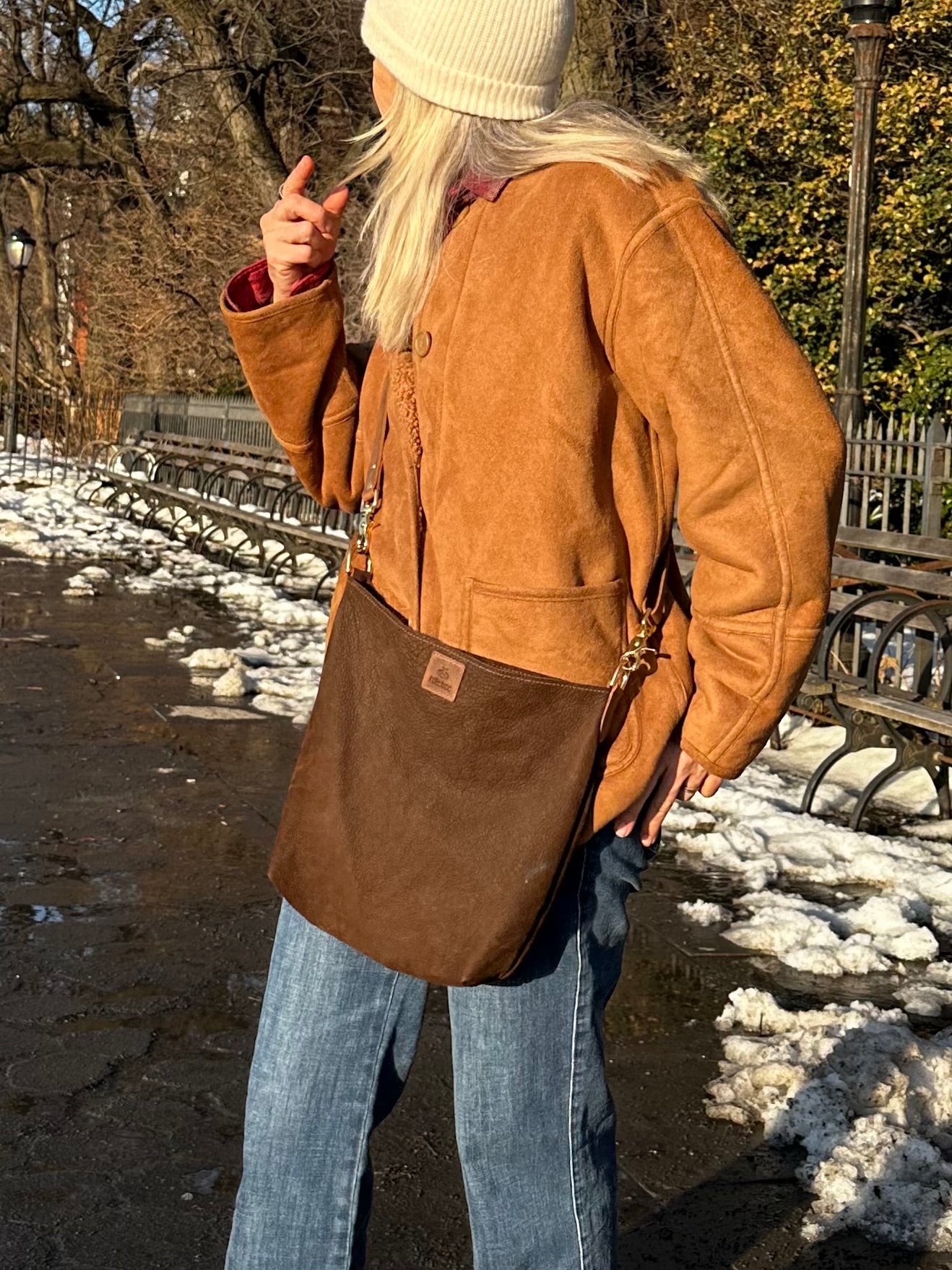 Adjustable brown leather bridle strap and brass hardware detail on The Slouch crossbody bag