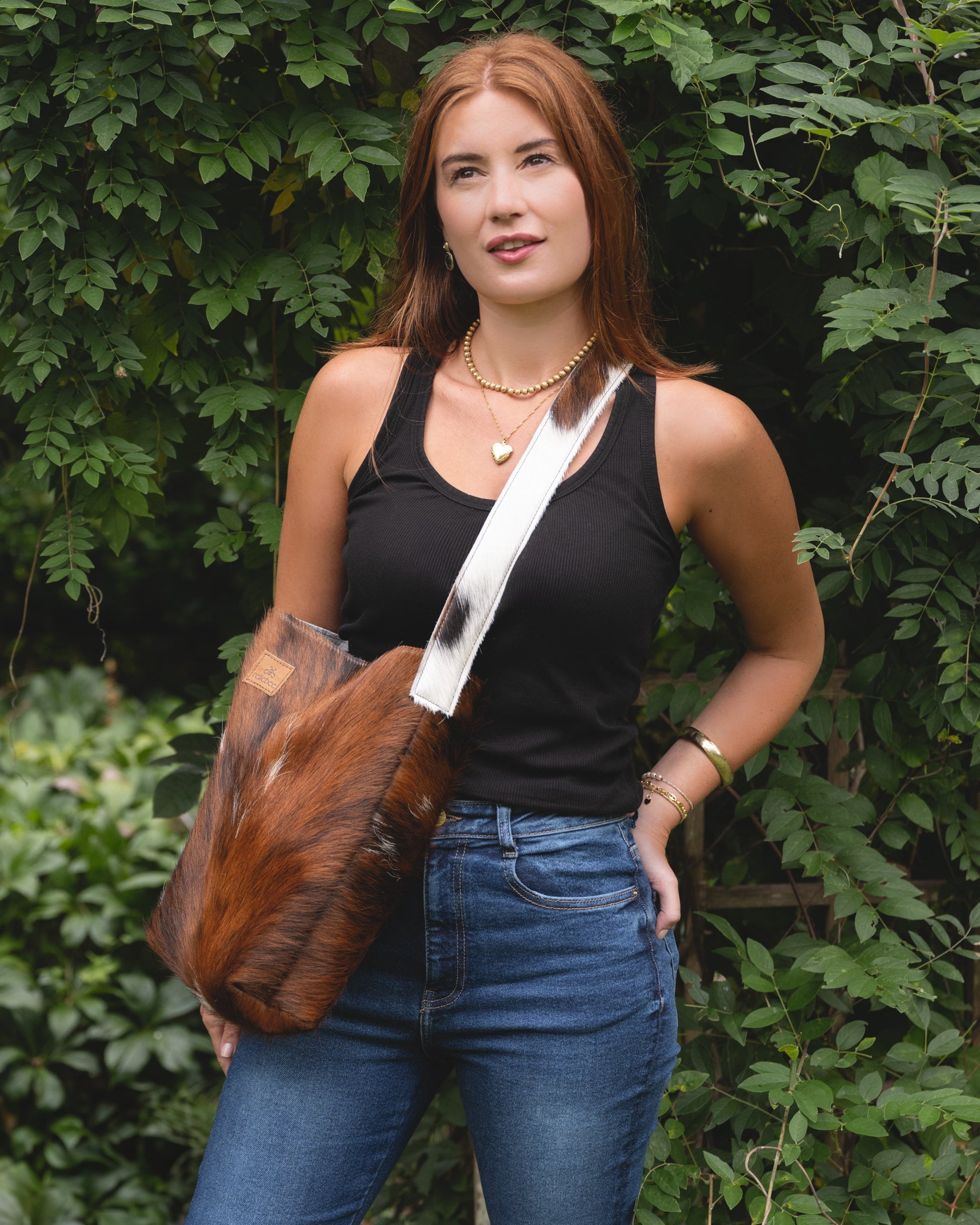 Image of model wearing the product Sierra Slouch.  The Sierra Slouch is a casual bag. Made up in a rugged Guernsey Brindle hide with a mix of brown, black and cream. The longer strap is great worn across the body or over the shoulder. The Sierra holds it all: clutch, wallet, water bottle and all else. No frills. Each Sierra is unique and markings will differ depending on cutting placement.  