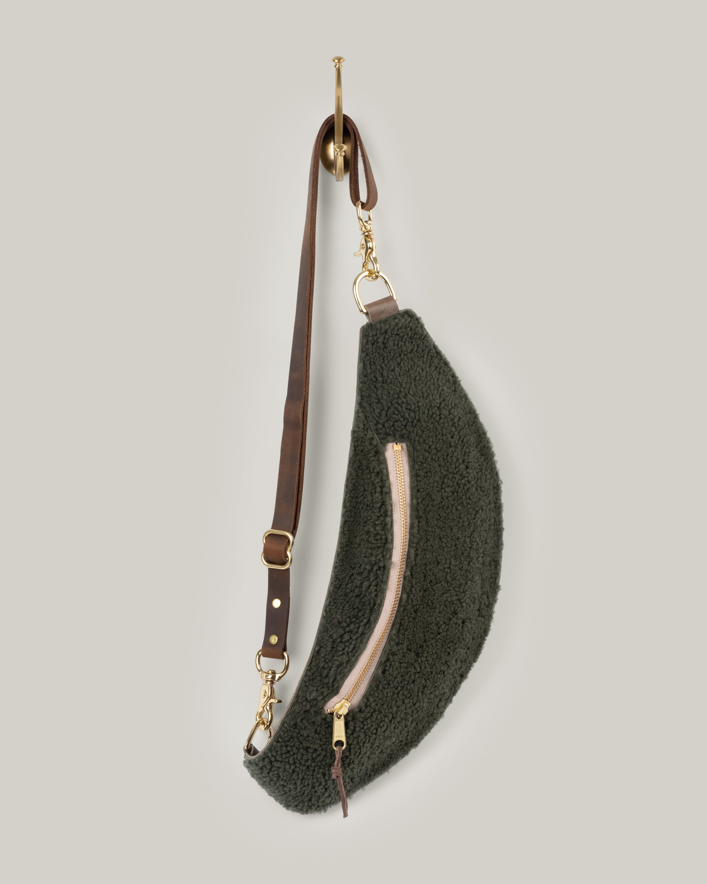 Image of the product Classic Sling: Shearling. The color Spruce adds a level of casualness and fun. You won't want to take this cozy bag off. It's low profile and gently hugs your body. Just big enough to hold your phone, keys, mini wallet and chapstick. Adjustable bridle leather straps. Sturdy top of the line antique brass hardware and zipper. Wear the Sling to that fun music festival, brewery or to wherever adventure leads you. It's the perfect travel companion.