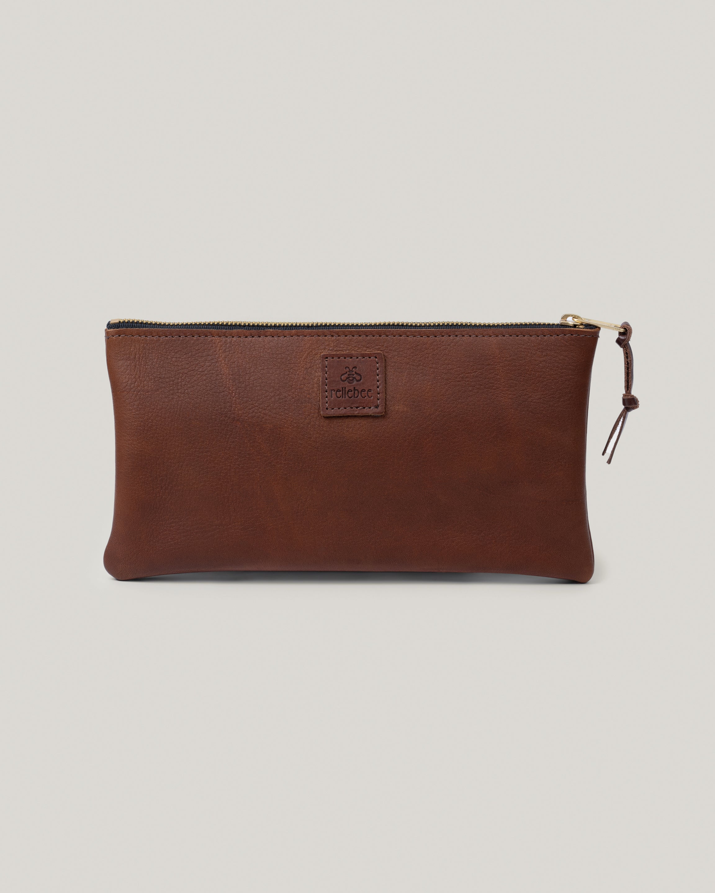 Image of the product The Clutch in saddle brown: the perfect bag for a night on the town or for just being out and about. It holds your phone, snap wallet, sun glasses, keys and lip balm. Pretty brass zipper gives it a nice pop. It's all you need. Wristlet option available