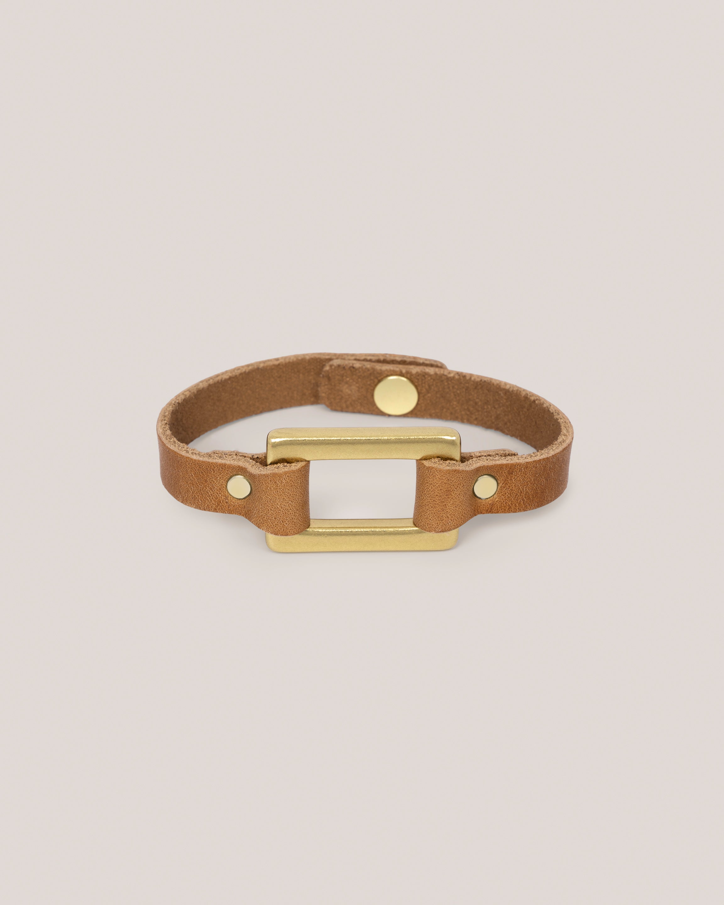 Image of the Stirrup bracelet in sand: Made from sturdy 5 ounce full grain leather. A nod to the horse country. Dress it up. Dress it down. Looks great layered. Pretty polished brass rectangle ring adds a touch of sophistication. Made by our leather craftsmen friends in Wyoming.&nbsp;