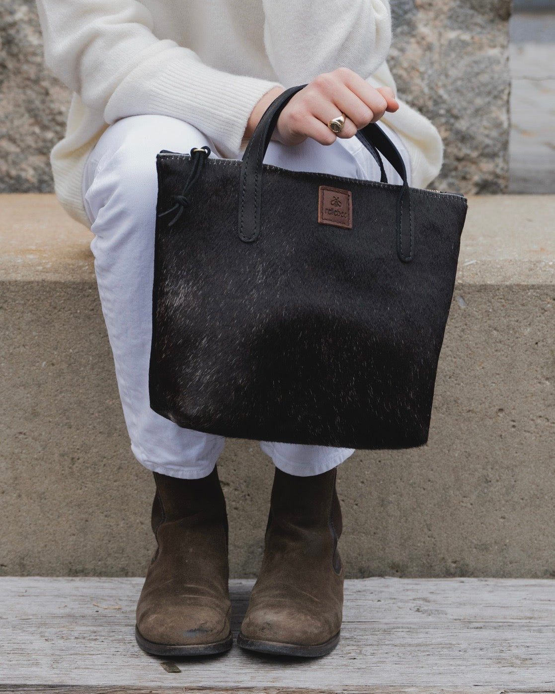 Close up image of model holding The Tuscan tote in black.