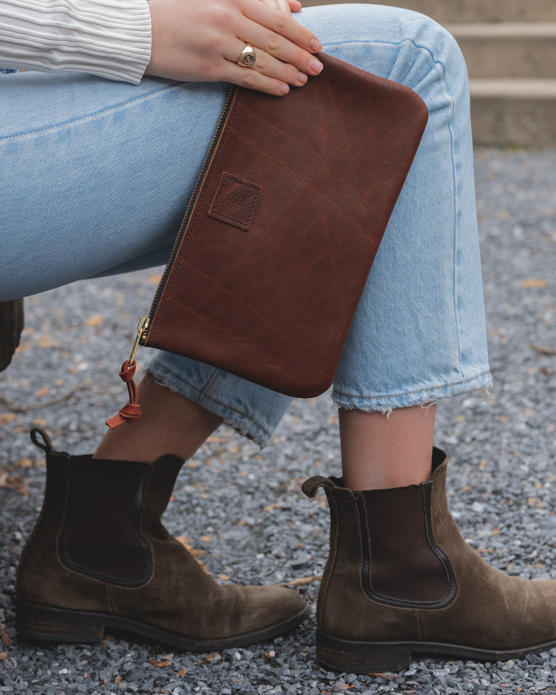 Side view image of the model sitting and holding The Clutch in saddle brown by their ankles 